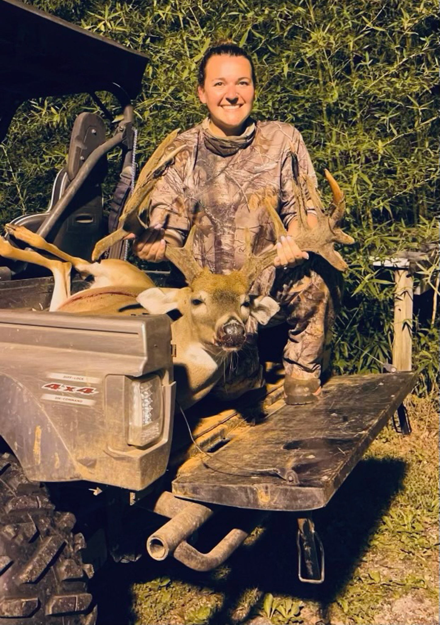 hunter in back of UTV with a buck.