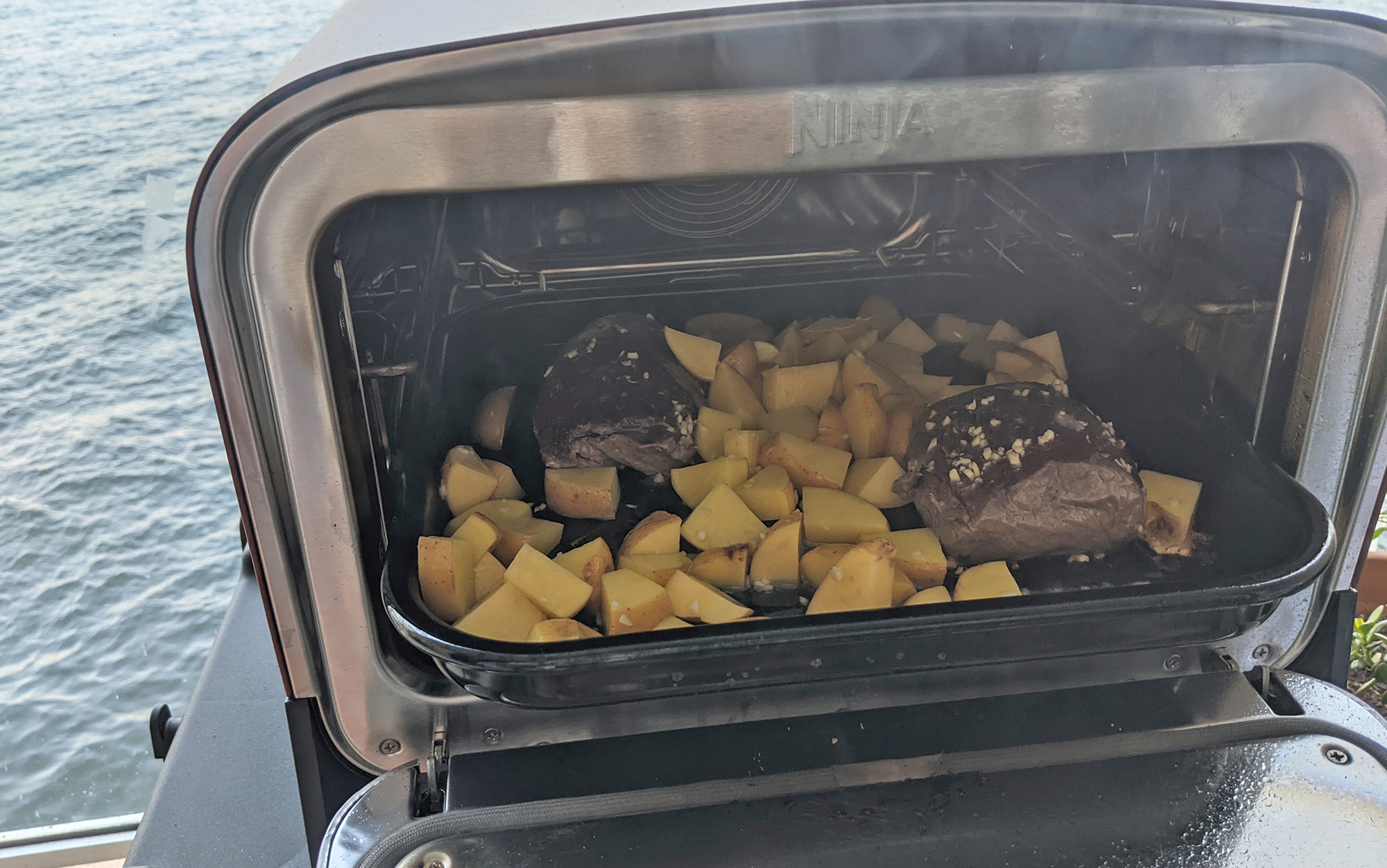 Potatoes and venison going into the Ninja Woodfire 8-in-1 Outdoor Oven.