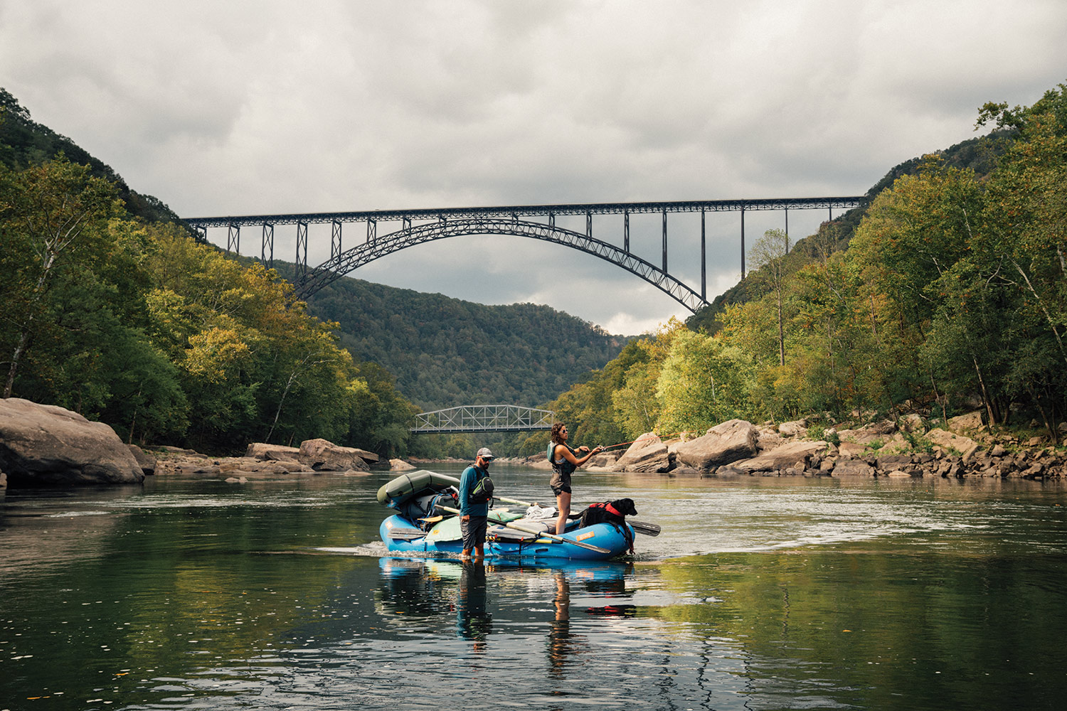 Anglers cast into river in front of New River Gorge Bridge.