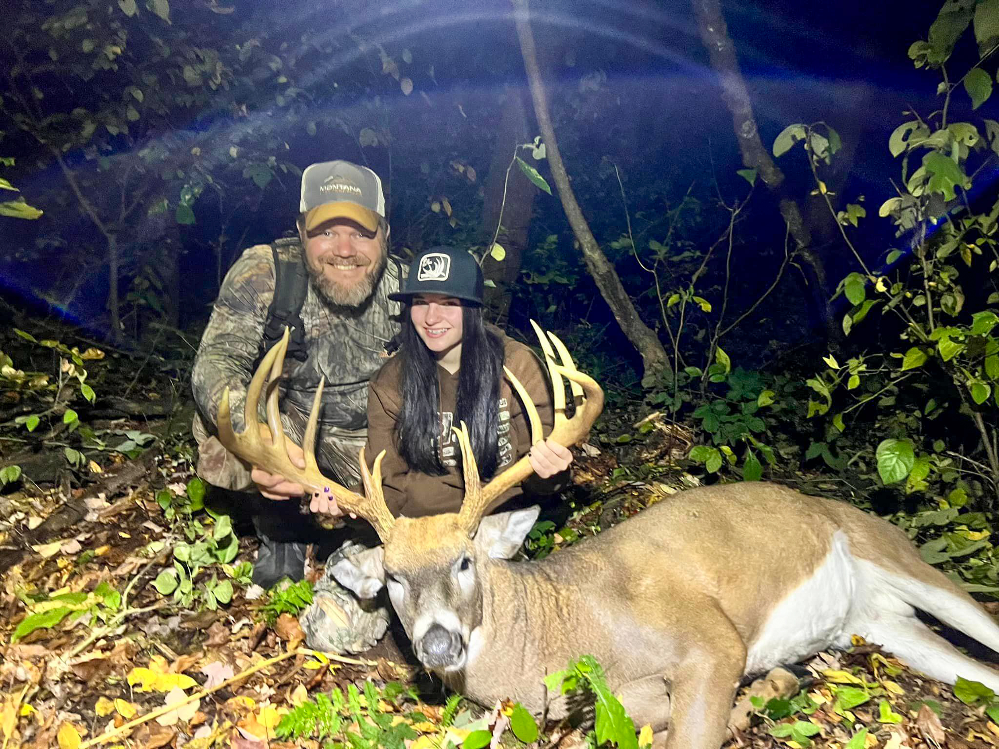 Father and daughter sitting behind a nice buck.
