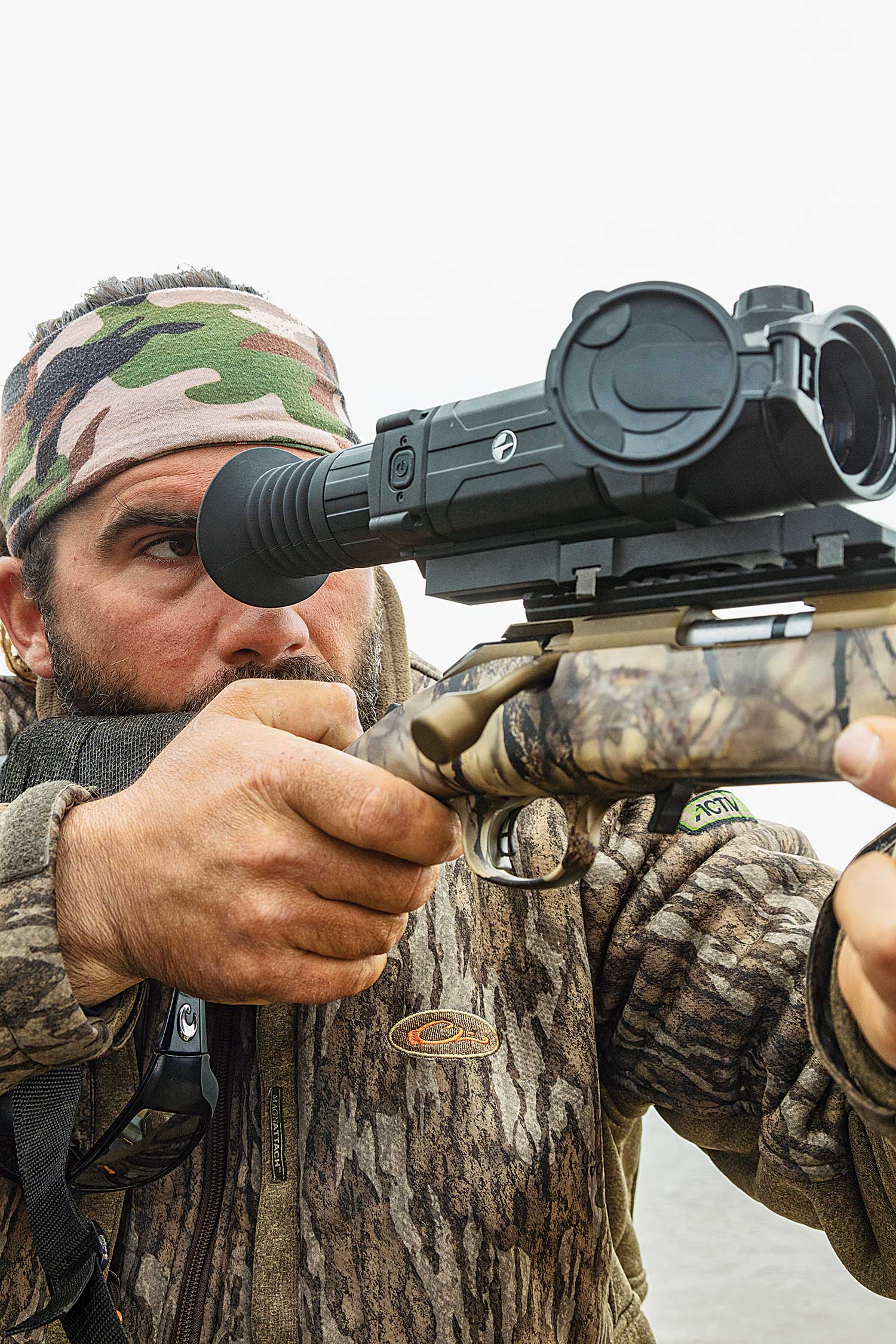 hunter peers through thermal scope atop rifle