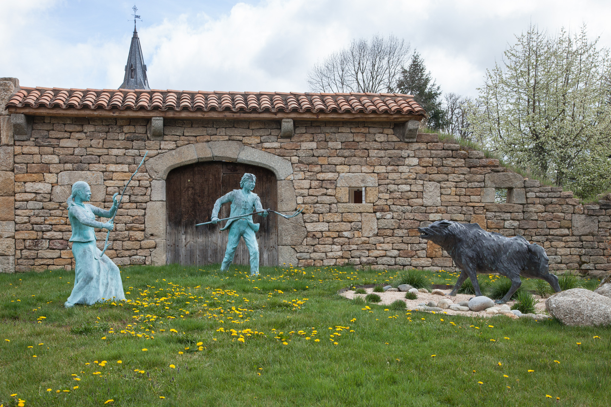 Two copper statues of peasants defend themselves from the Beast of Gévaudan.