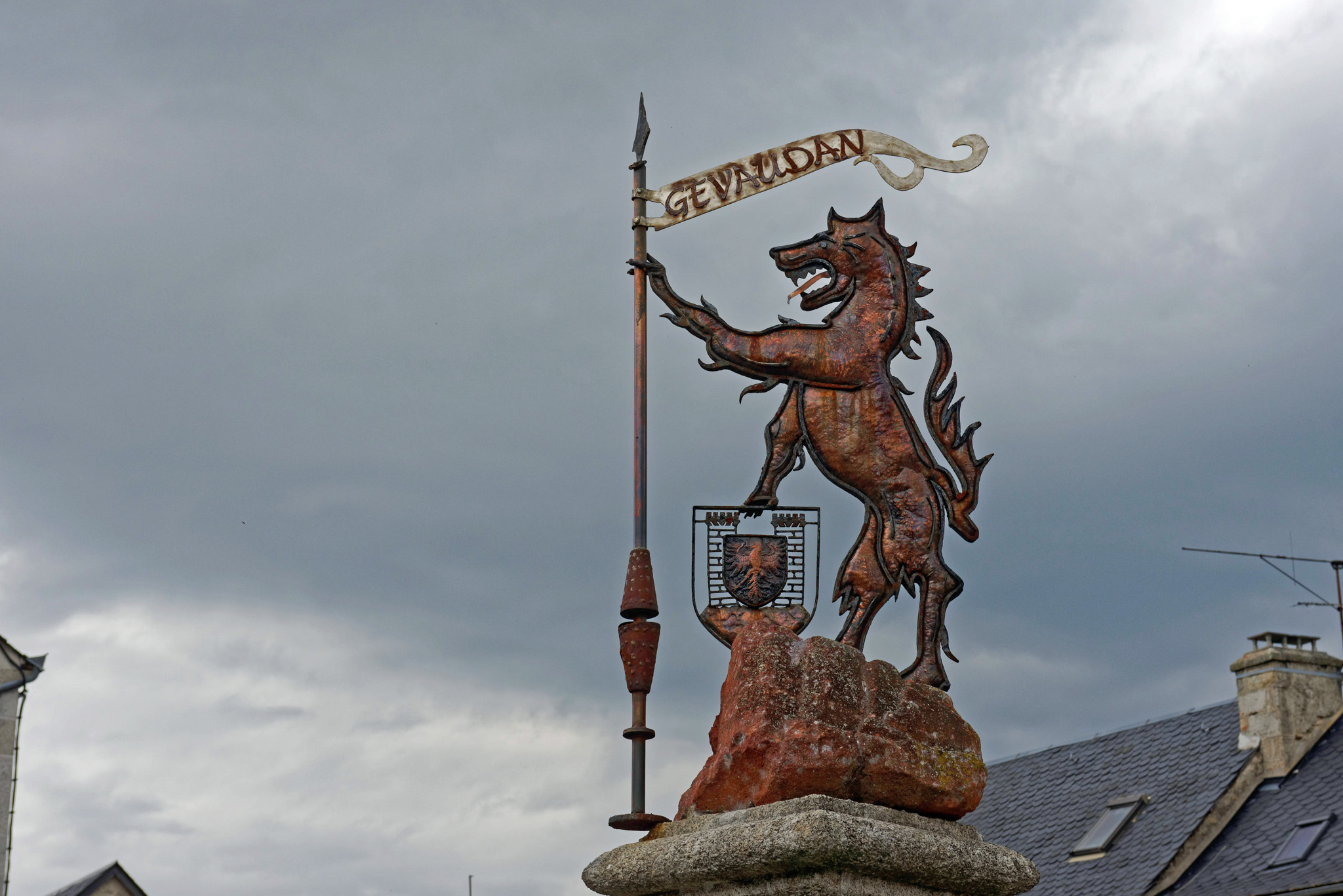 A statue sign of a beast with a rampart over rooftop villages.