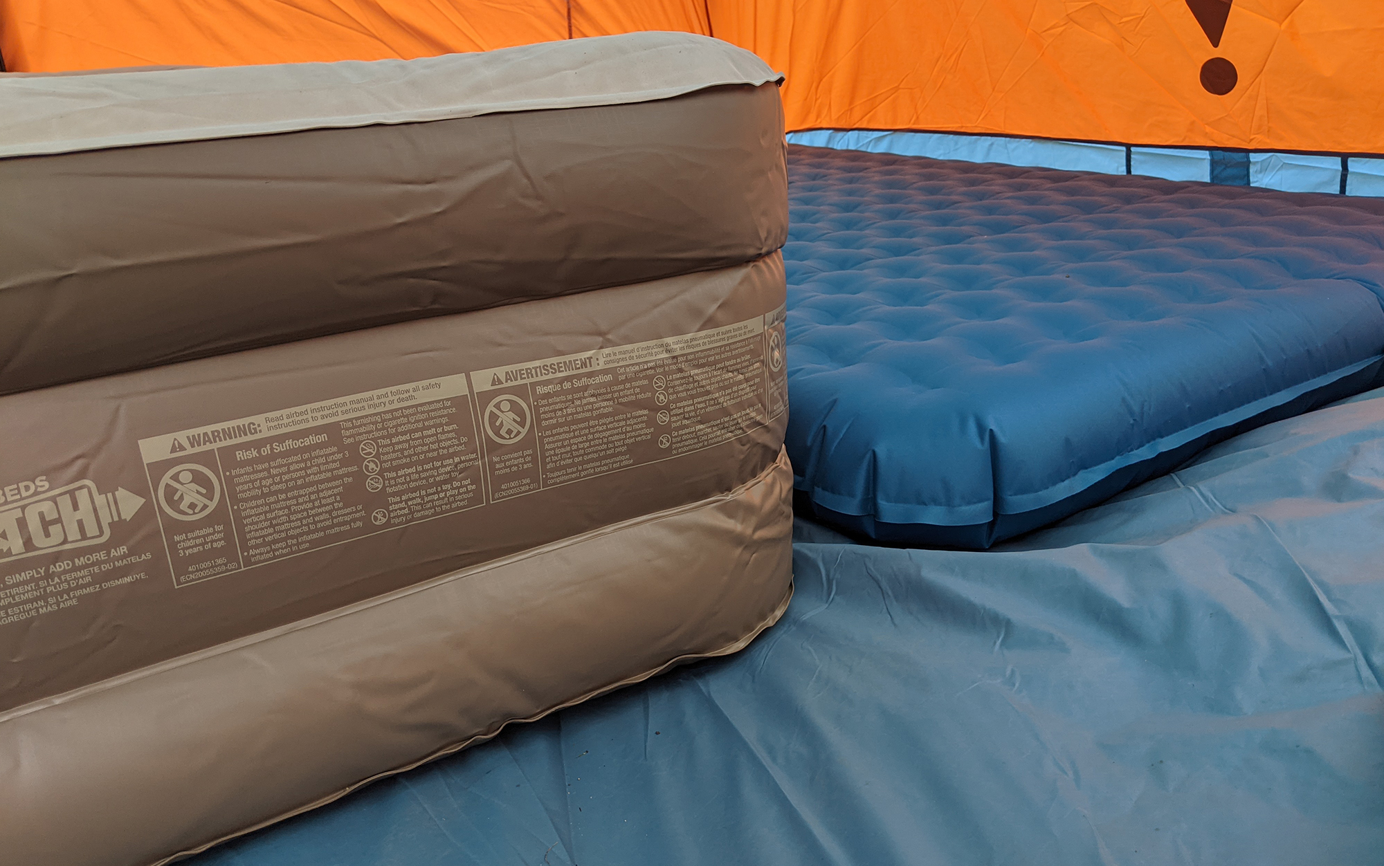 Two air mattresses sit in a tent.