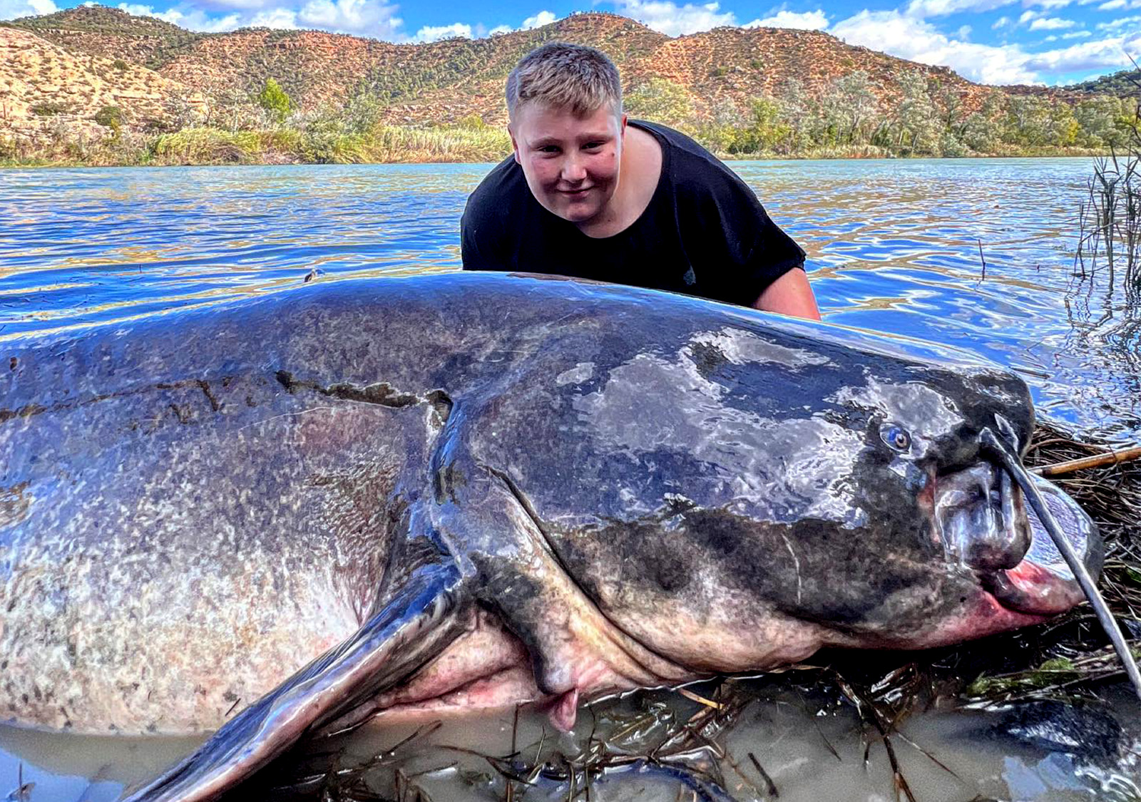 A British boy catches a monster catfish almost twice his size
