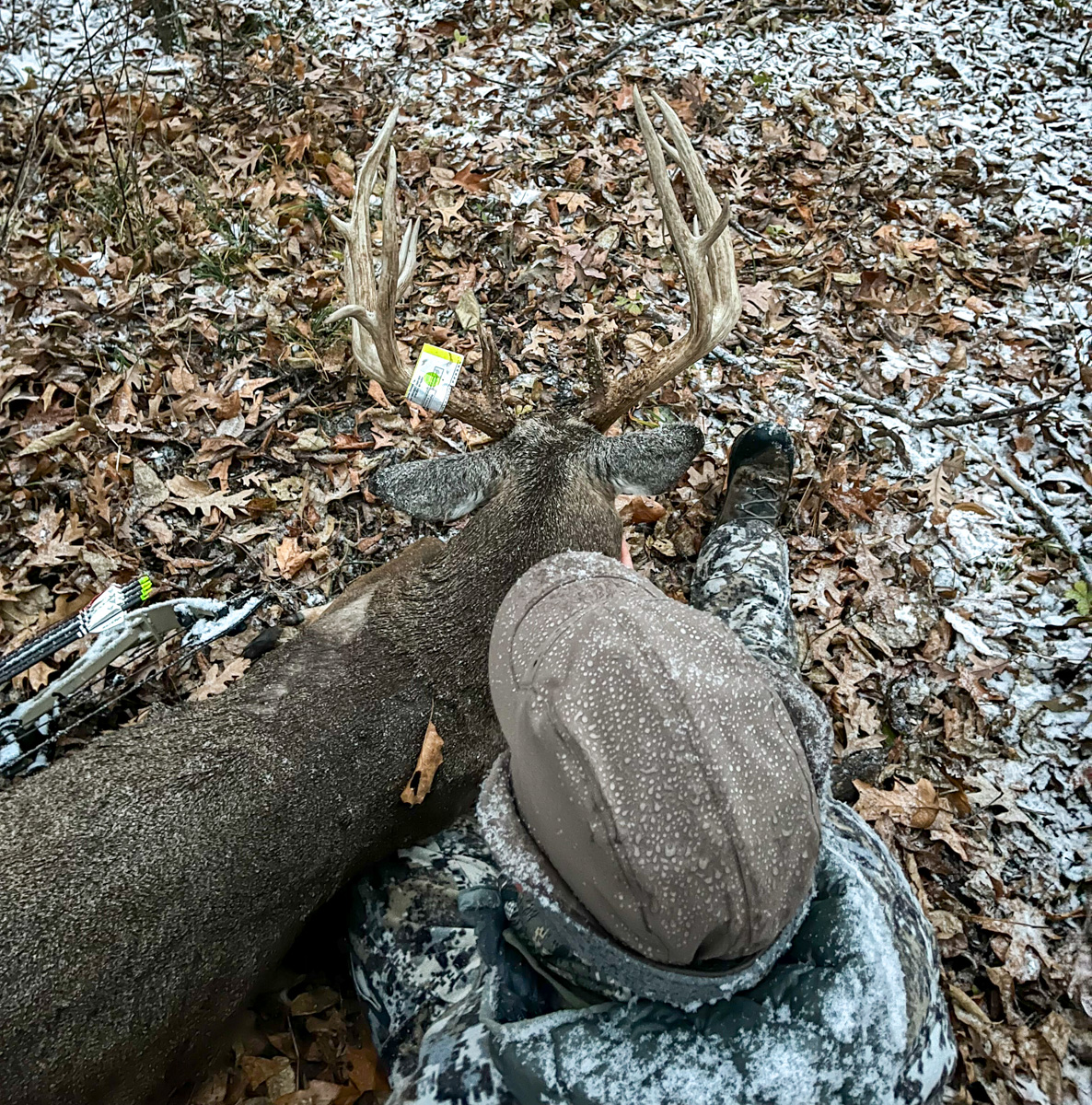 An overhead shot of a hunter's head and the back of a big buck's antlers.