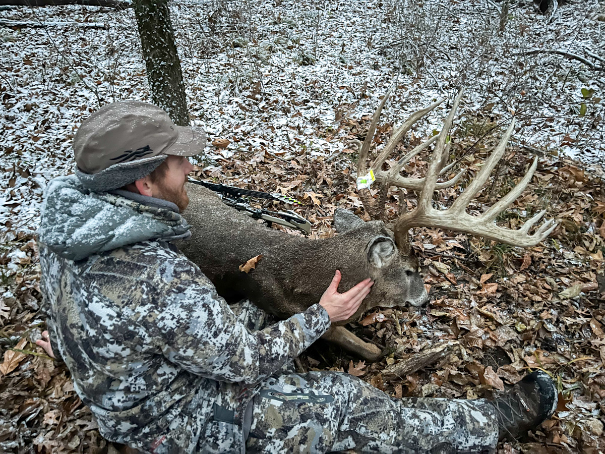 A hunter admires the antlers of a big buck.