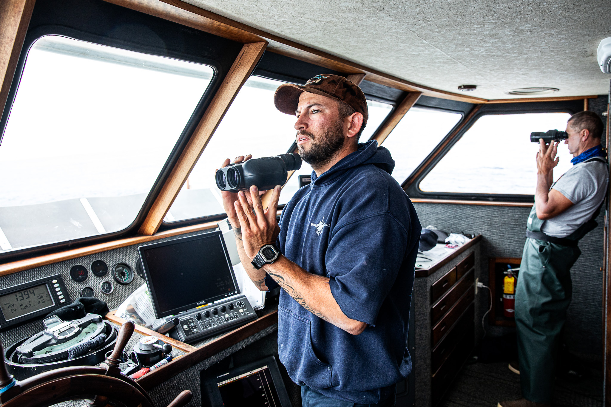 A captain at the helm of a charter ship scouts for fish.