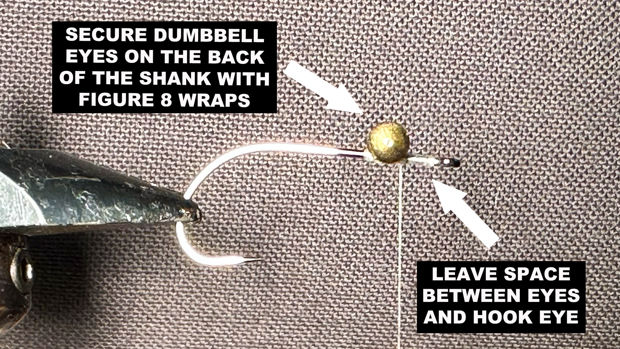 A hook in a fly-tying vise with instructions and arrows describing how to get started.