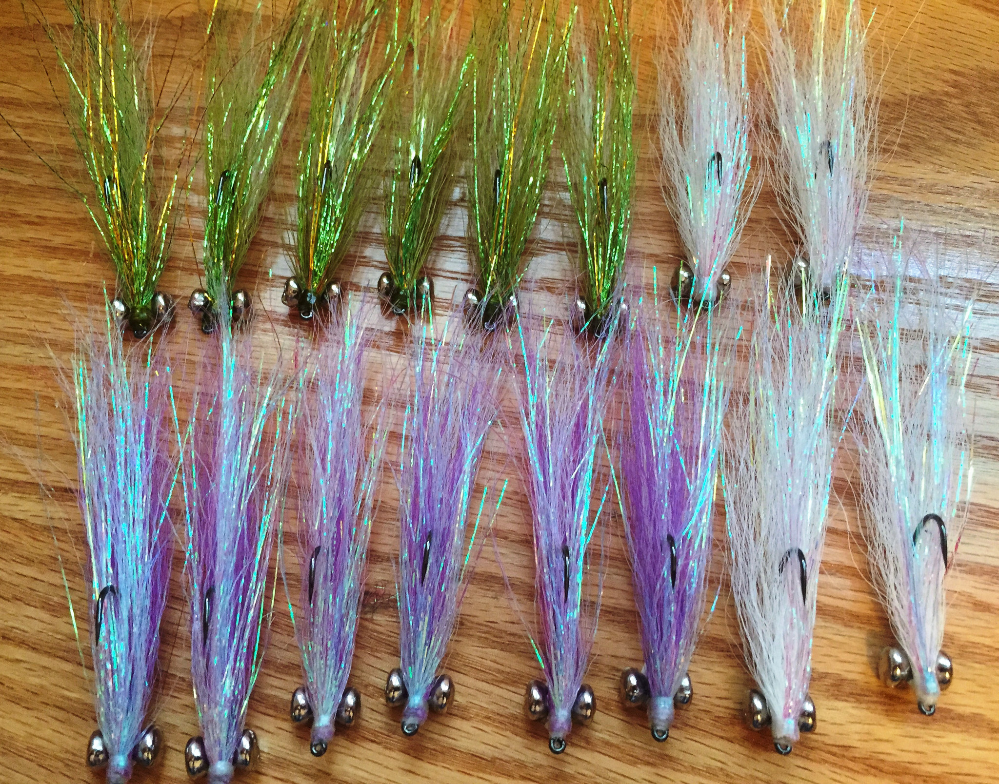 Two rows of hand-tied Clouser Minnow flies in white, chartreuse and purple.