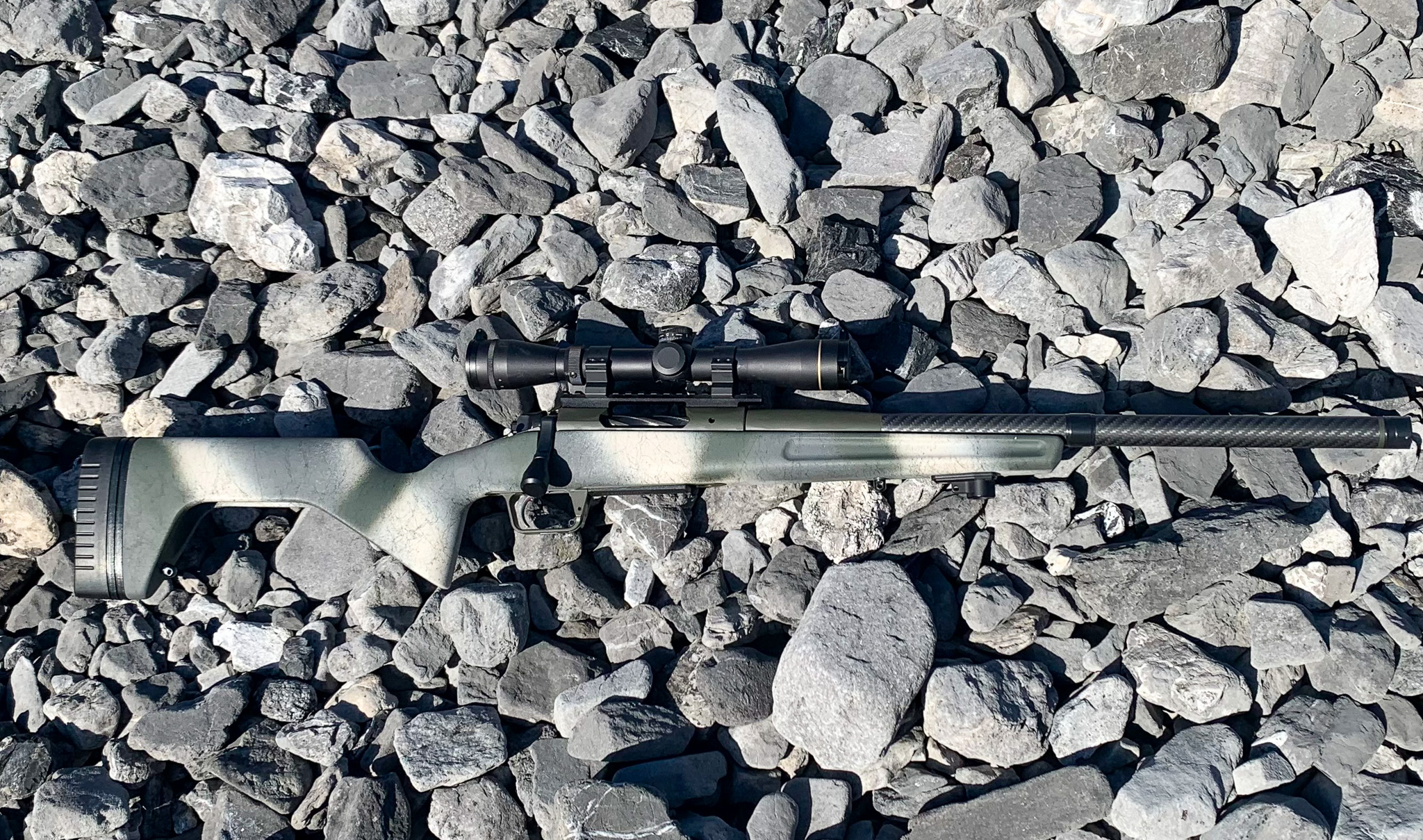 A sheep hunter's camo Springfield 2020 Redline chambered in 6.5 Creedmoor laid carefully on the rocks in the mountains.