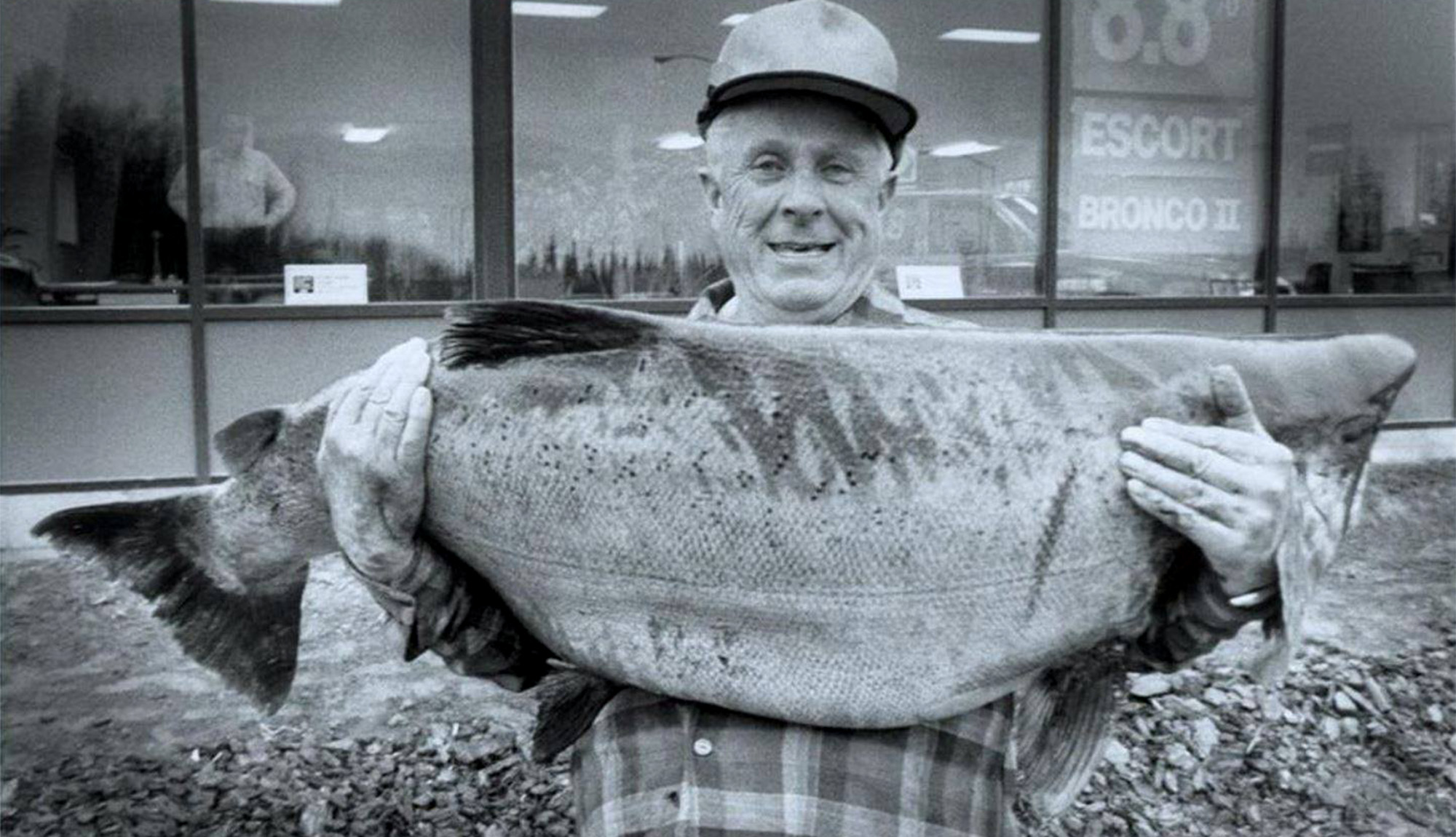 An angler holds up the all-tackle world record Chinook salmon.
