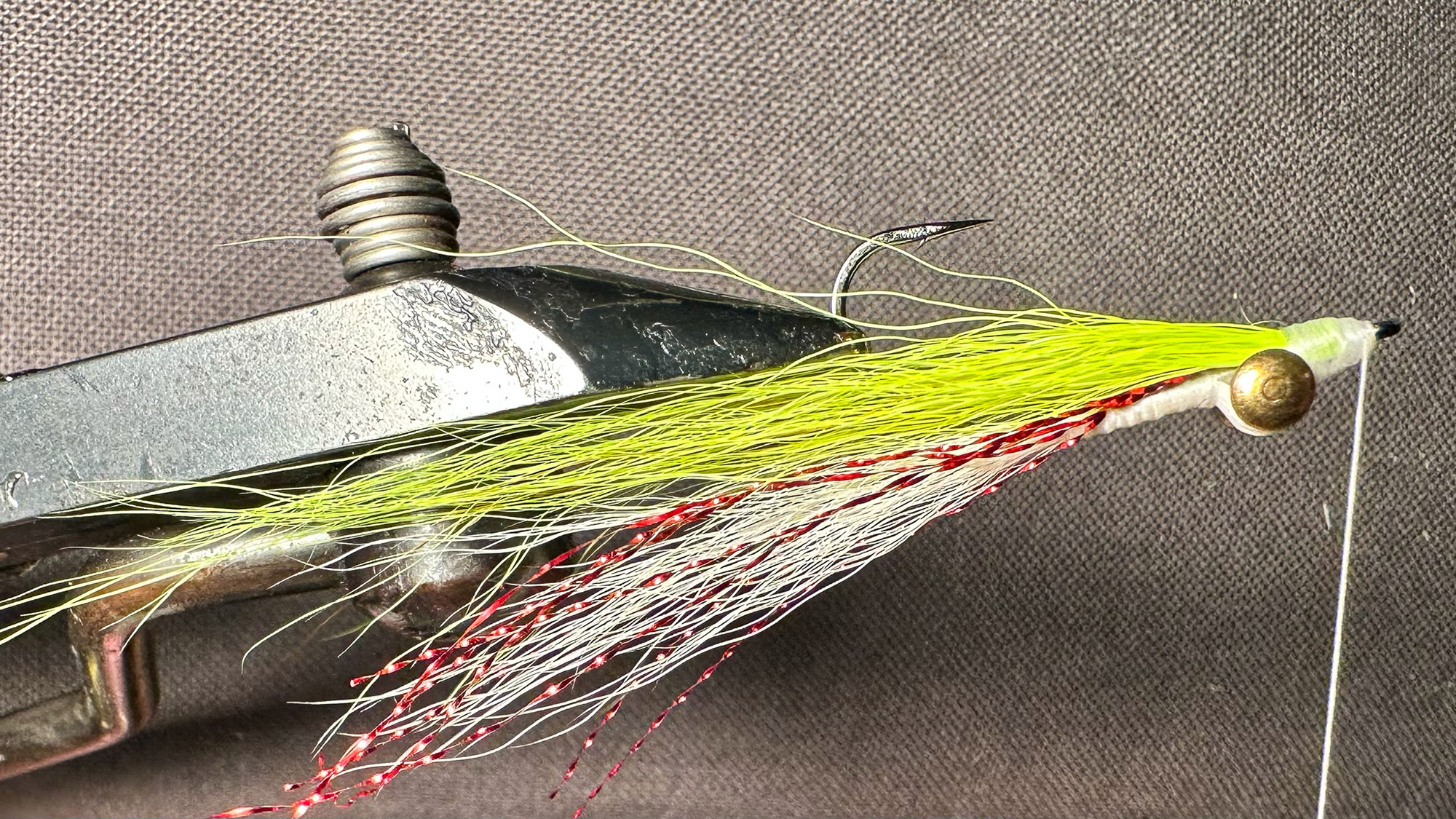 A hand-tied Clouser Minnow in a vise.