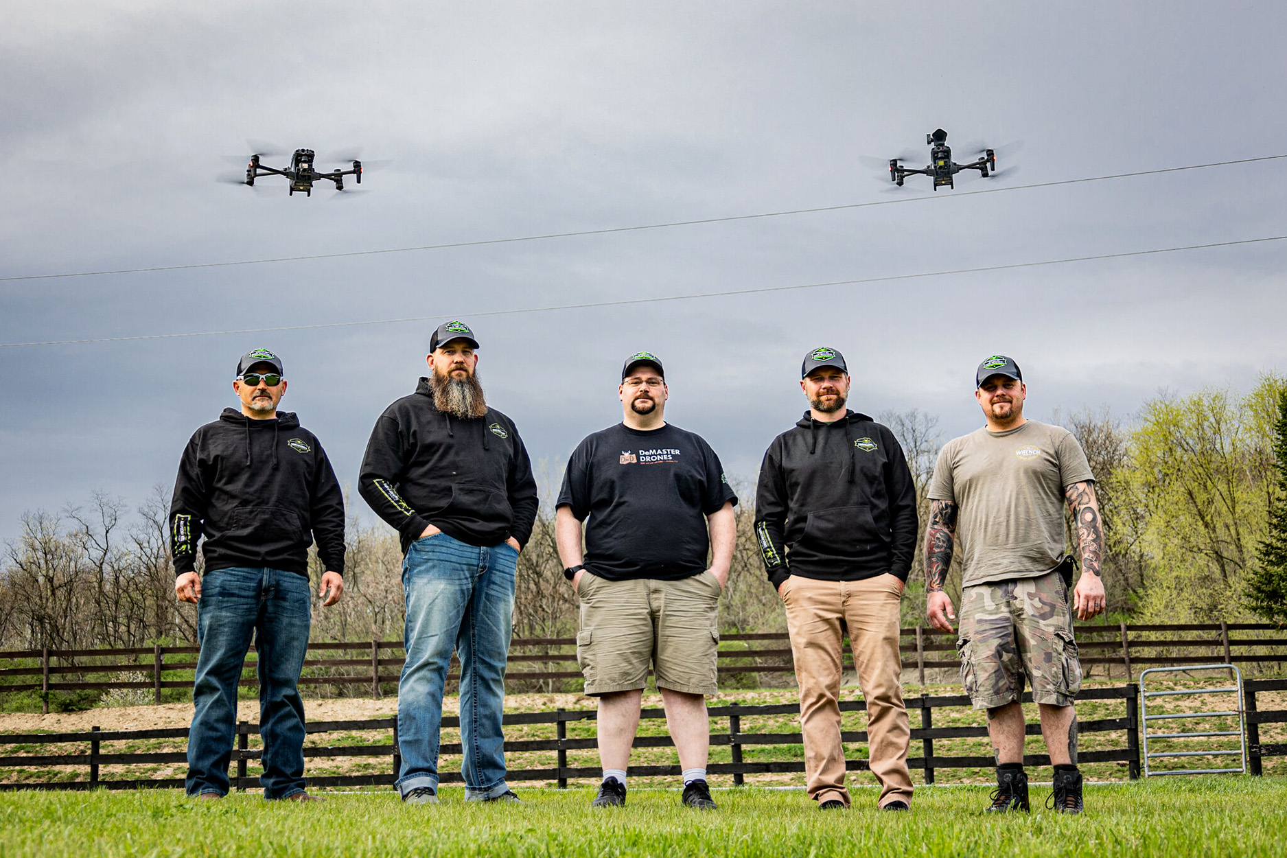 Five licensed drone pilots with drones flying overhead.