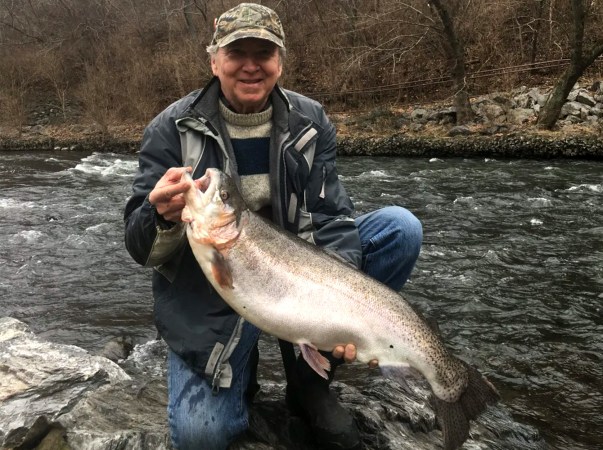 A fisherman holds up a fat rainbow trout caught from a creek in Maryland.