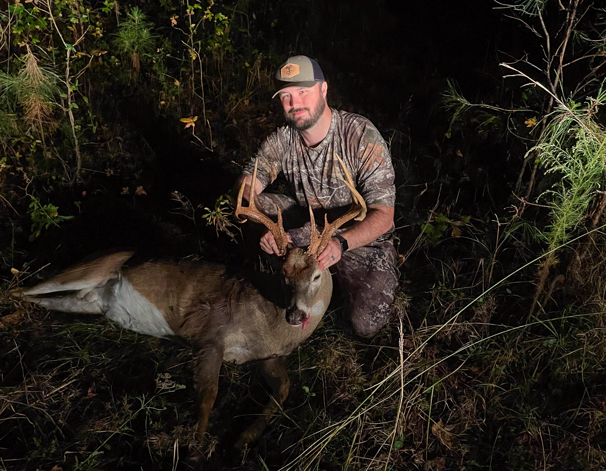 A hunter kneels with a nice buck.