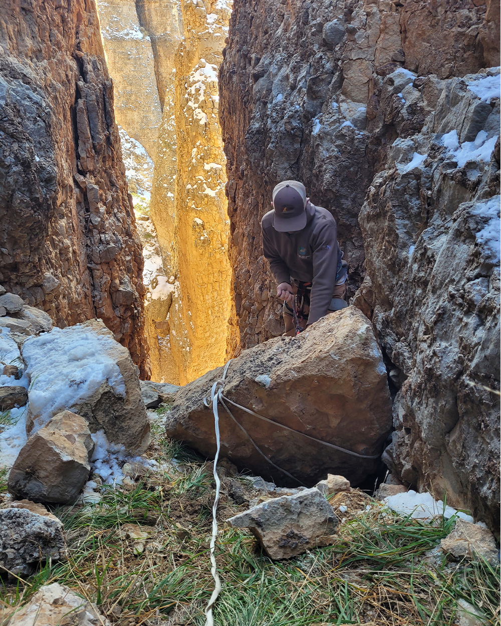 A man prepares to rappel down into a canyon.