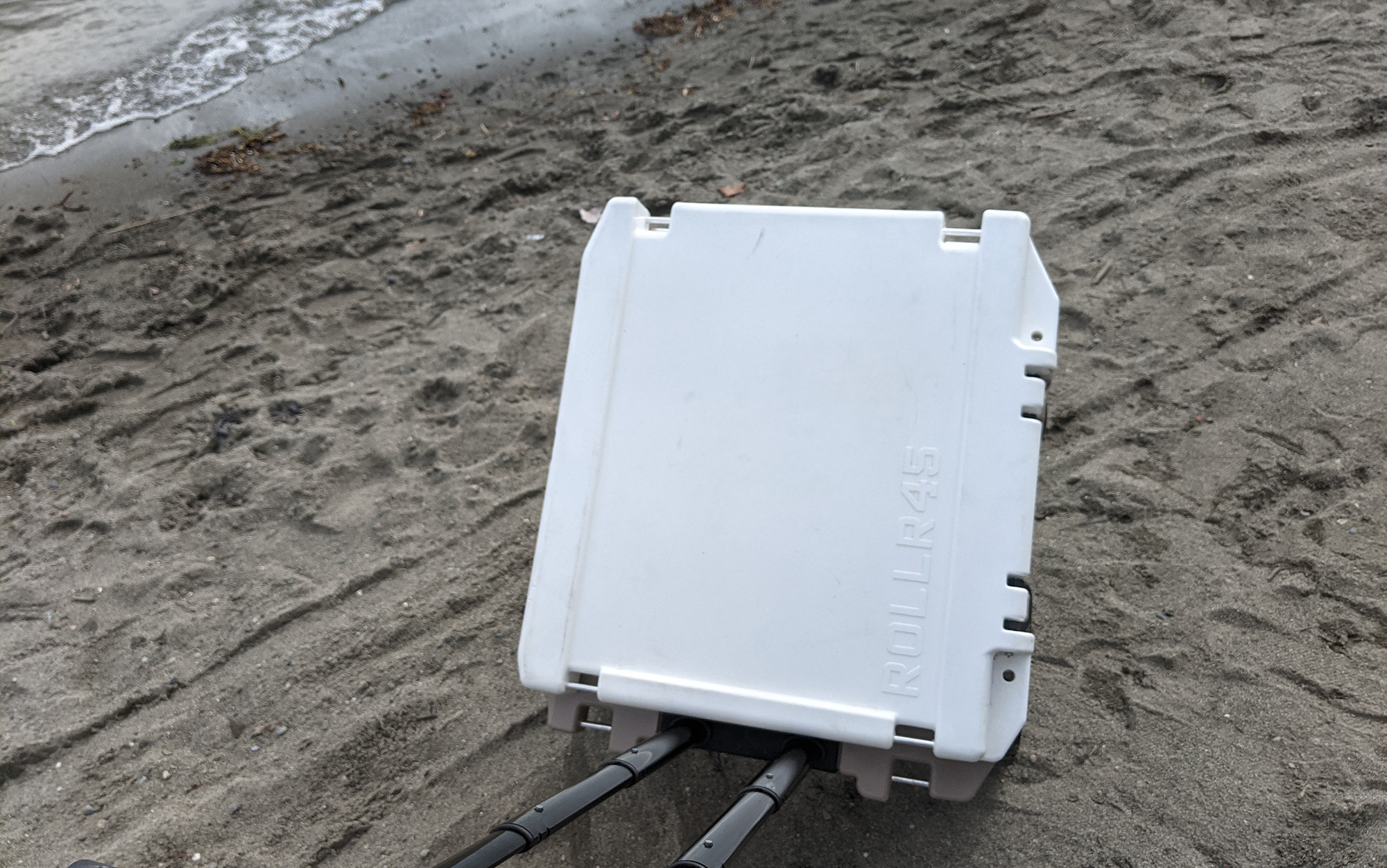 The Rover wheeled cooler is on the beach. 