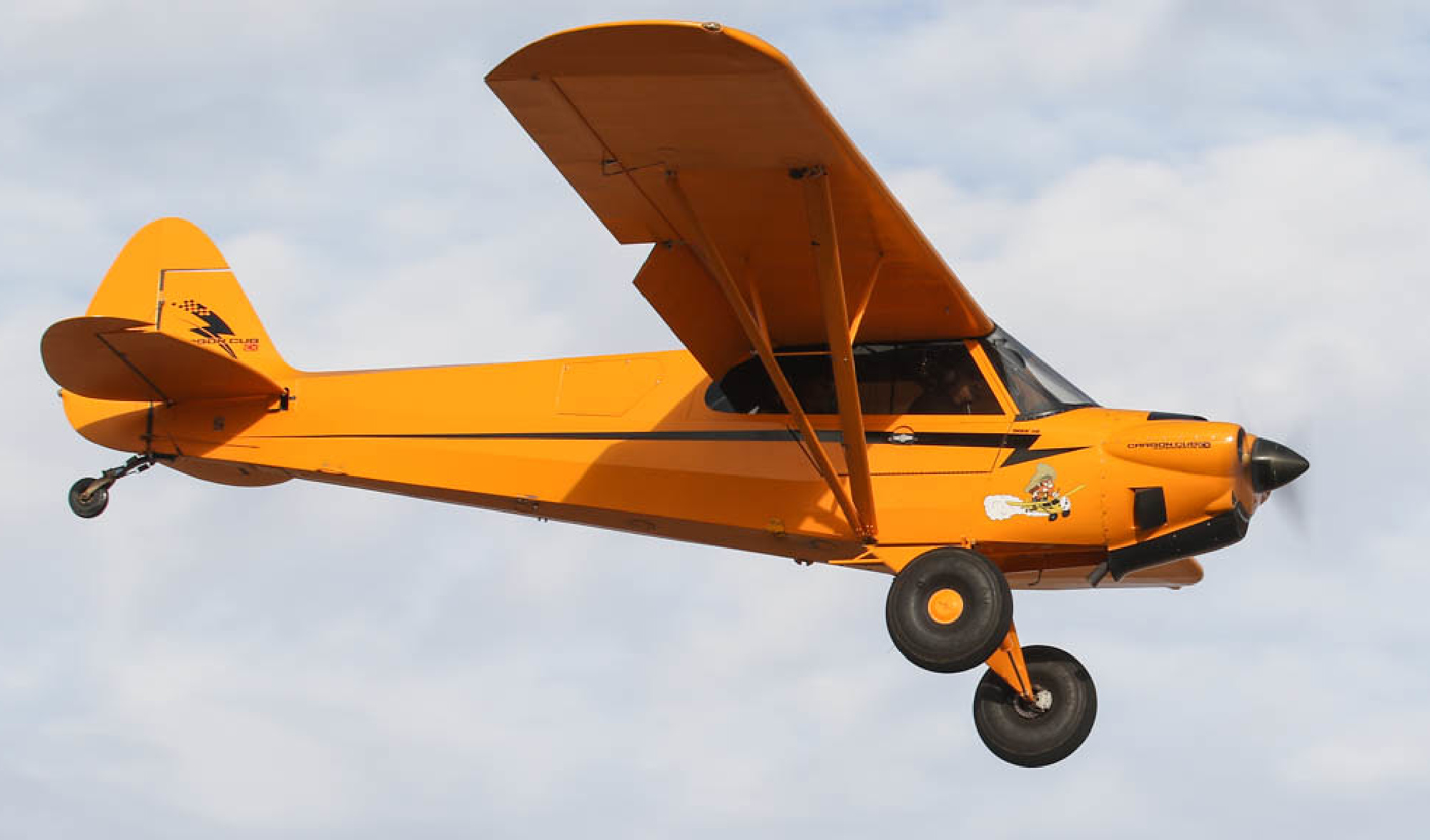 A Carbon Cub plane, the same model that Dustan Currier owned, flies through the sky.