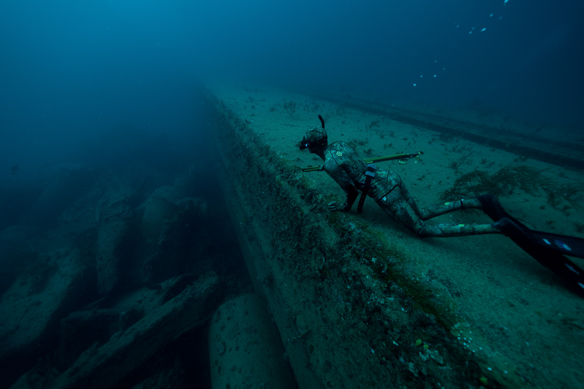 Spearfisherman rests on a wreck underwater.