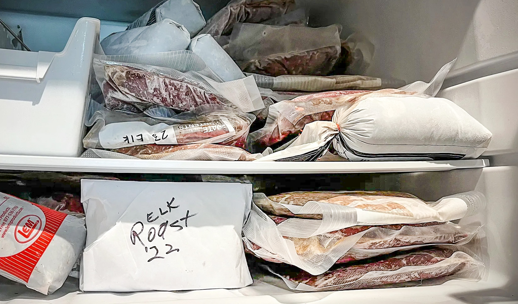 Packages of game meat are stacked up in a freezer.