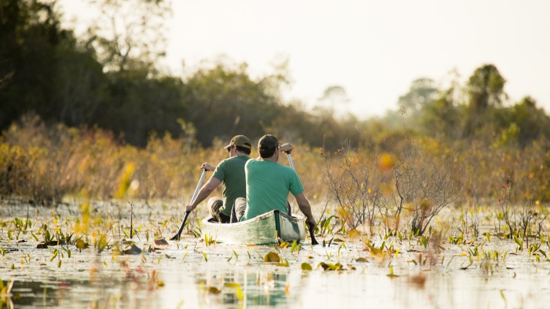 Two men paddle a canoe across Okefenokee National Wildlife Refuge.