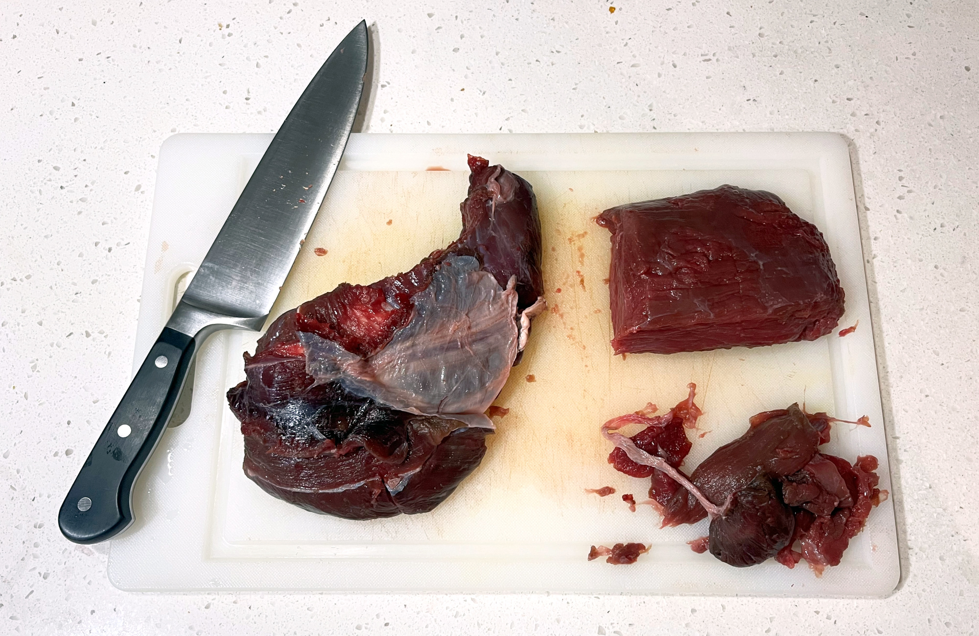 Cuts of elk meat on a cutting board with trim removed.