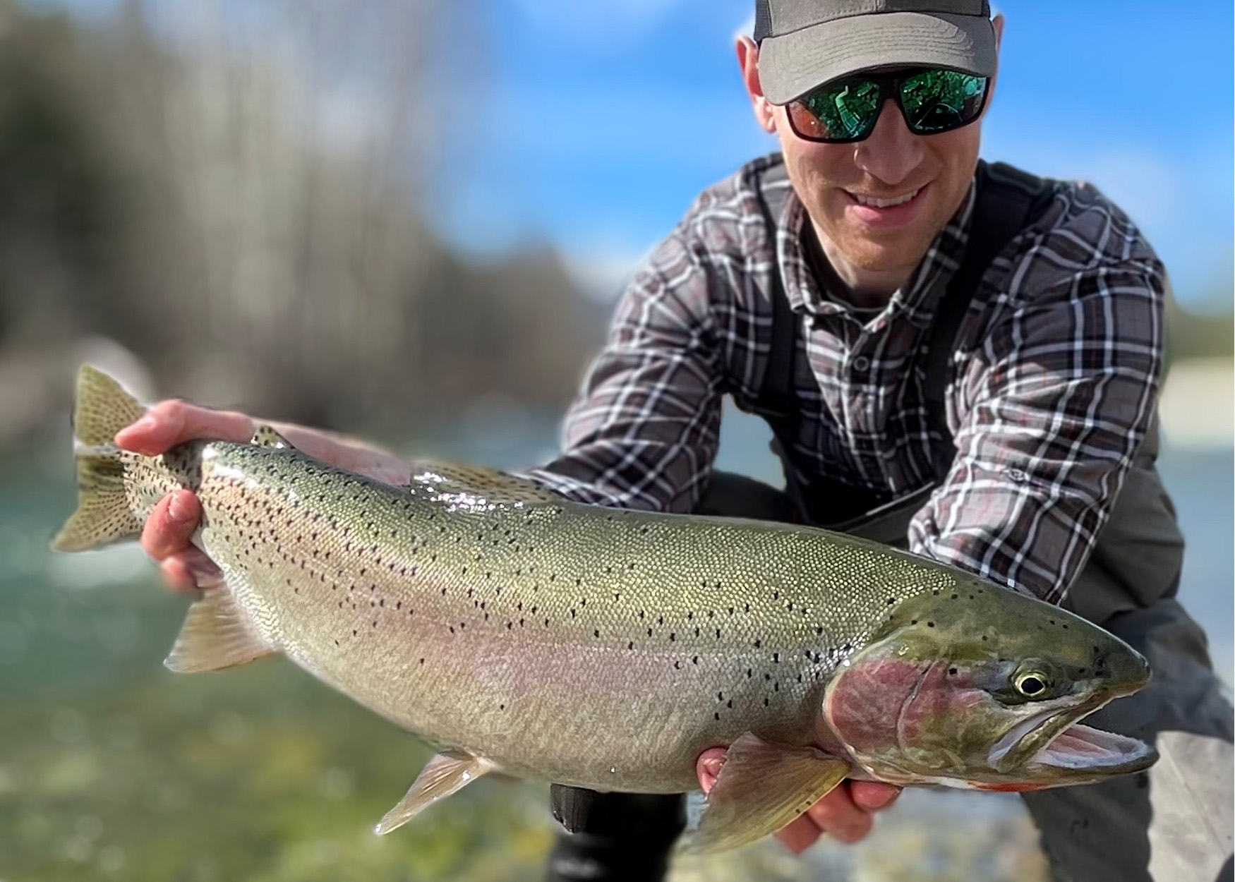 A fly fisherman holds up a state-record cutthroat trout.
