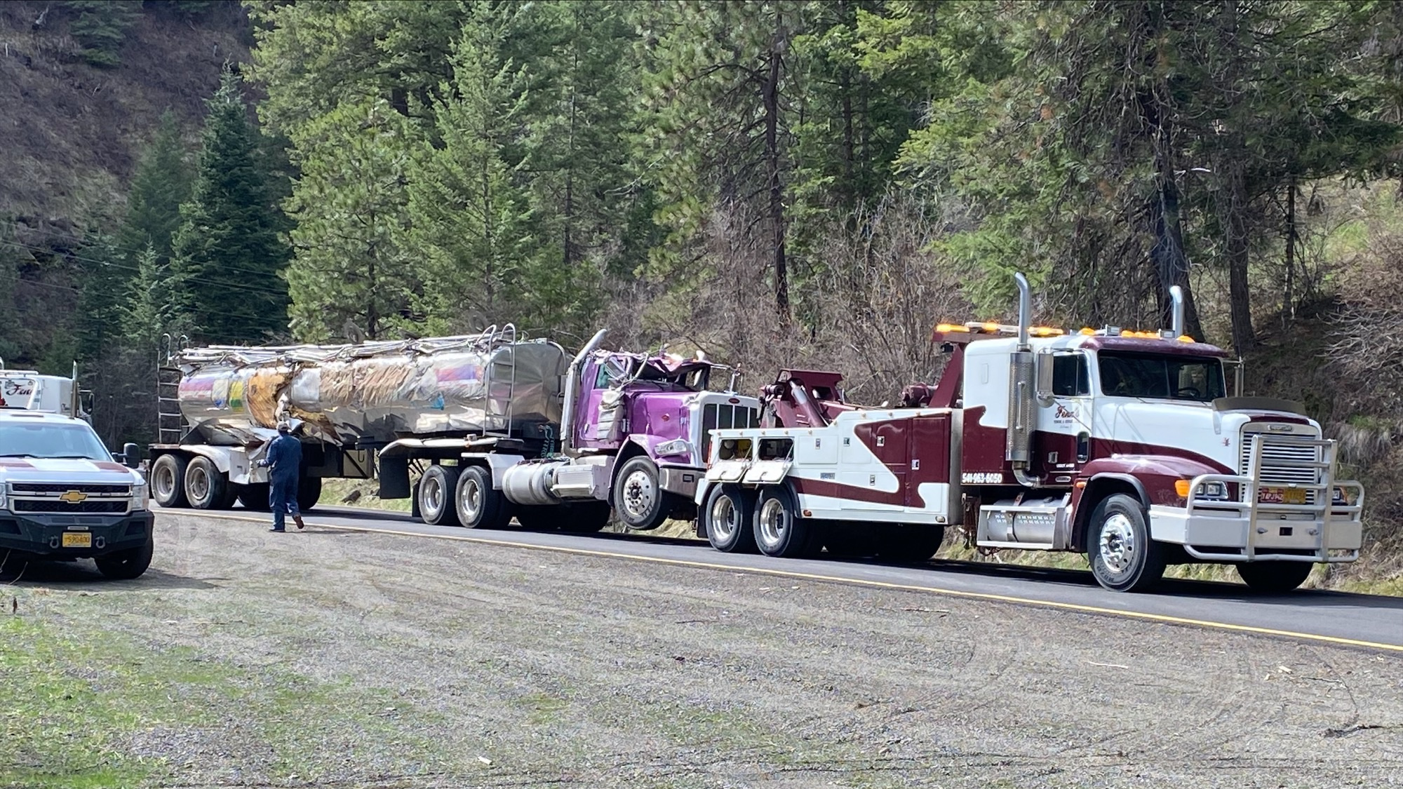 A wrecked tanker truck is towed from the crash scene.