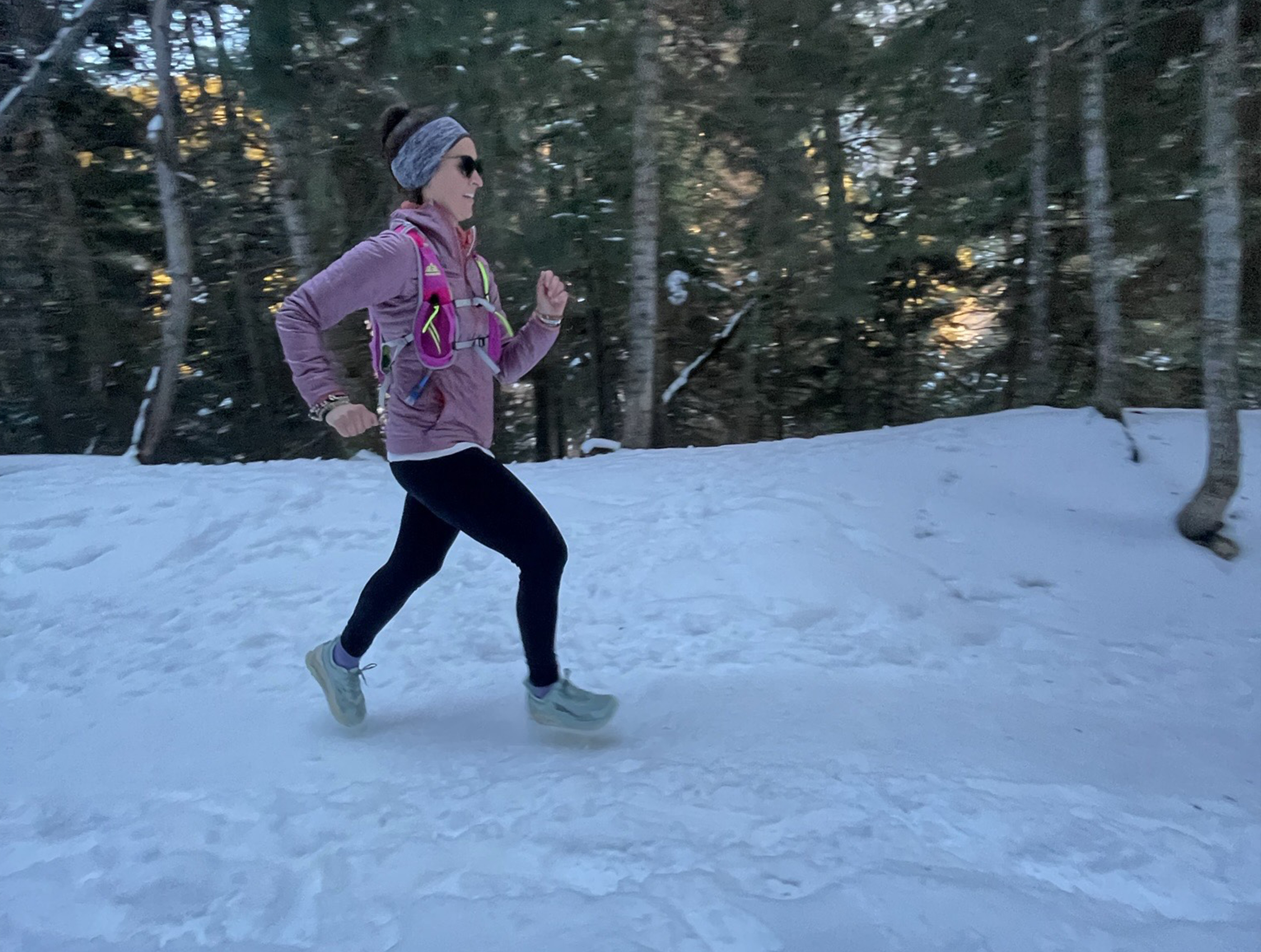 Woman runs in the Altra Olympus on snowy trail.
