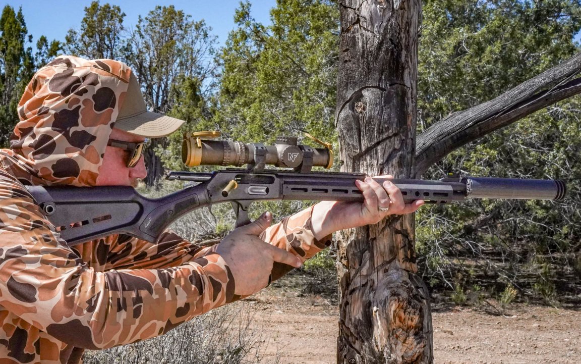 A man in a camo sun shirt and hood works the action of the Marlin Dark Series 1895 45-70