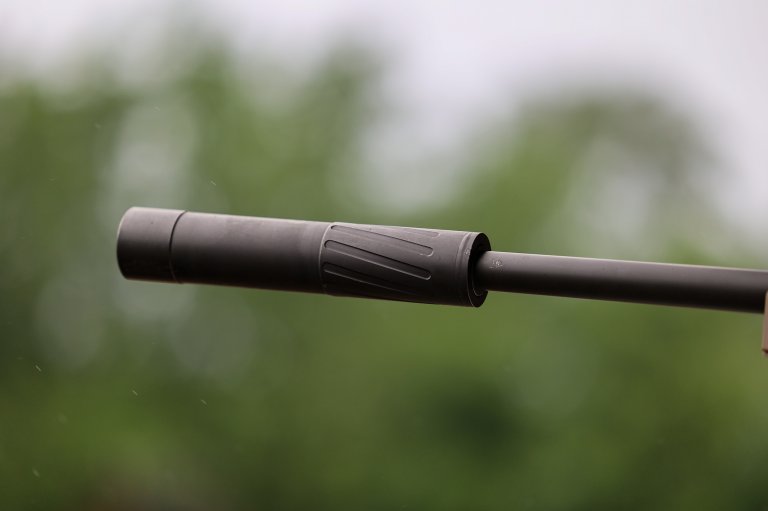 A rifle suppressor against a green background