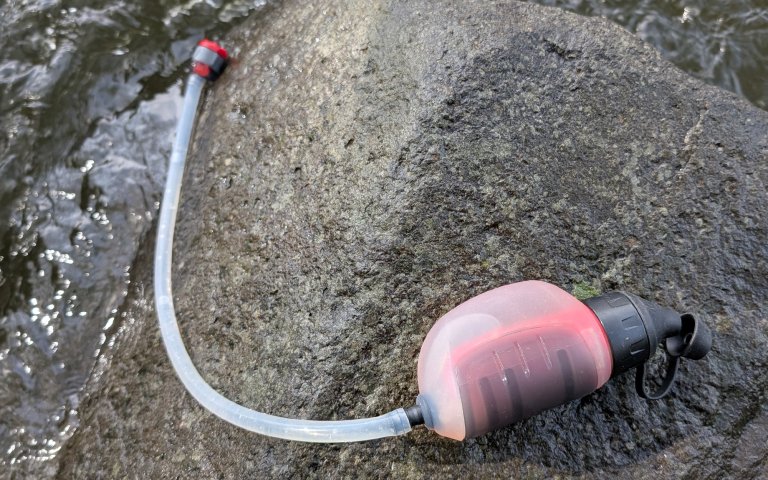 MSR Trailshot sitting on a rock with a river beneath it