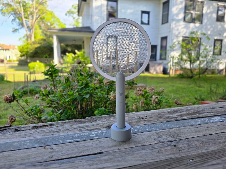 An electric fly swatter sits on a porch.