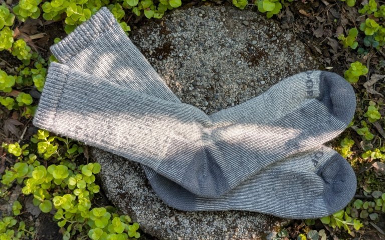 REI Midweight socks sitting on a round stone