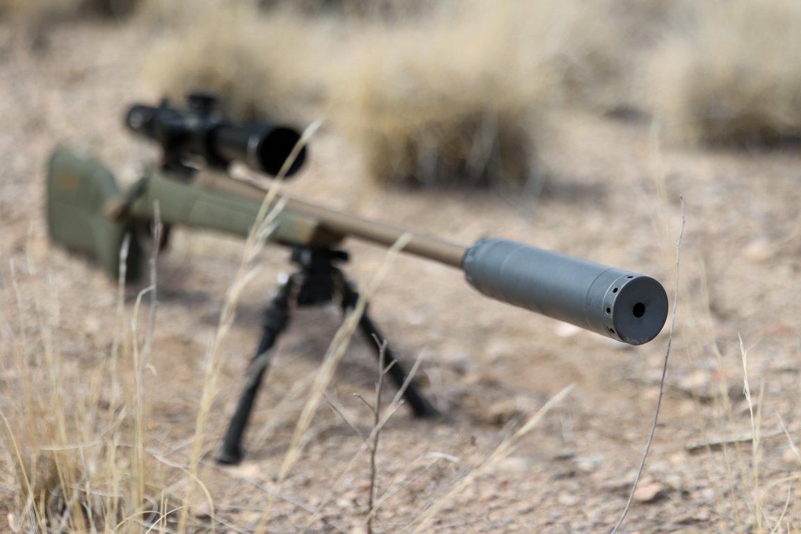 A hunting rifle with a suppressor on it