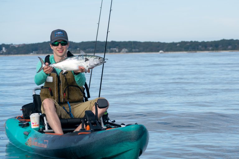 A kayak fisherman holds up a false albacore.