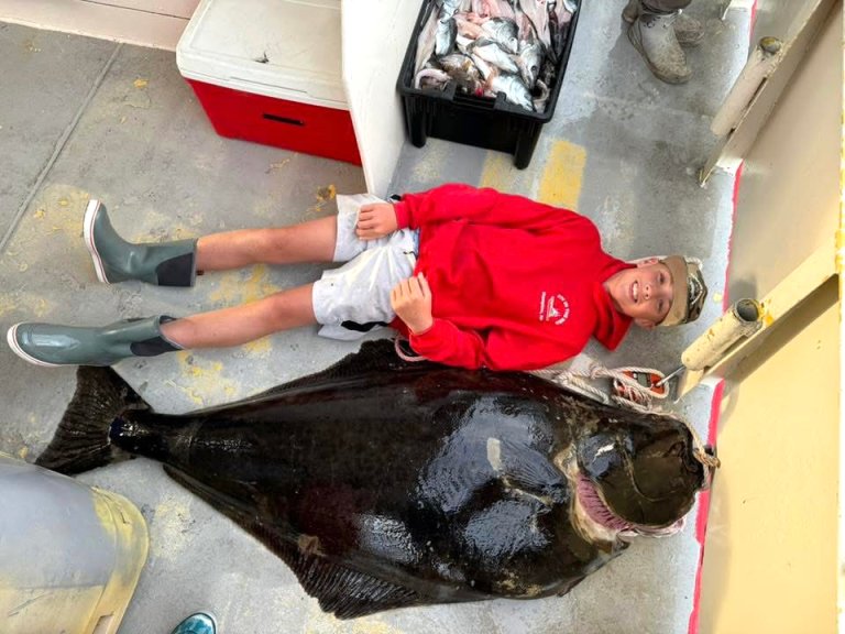 A kid lying beside a giant halibut that is the new junior world record.