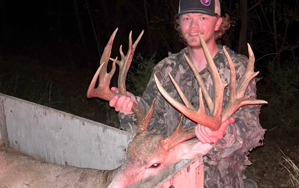 An Oklahoma hunter with a big buck with lots of points in the back of a wagon