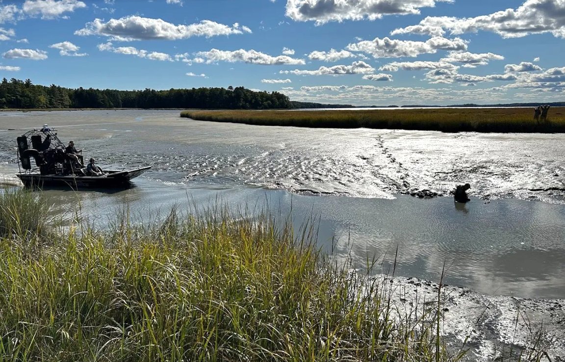 A photo of police rescuing a man stuck in mud in Maine.