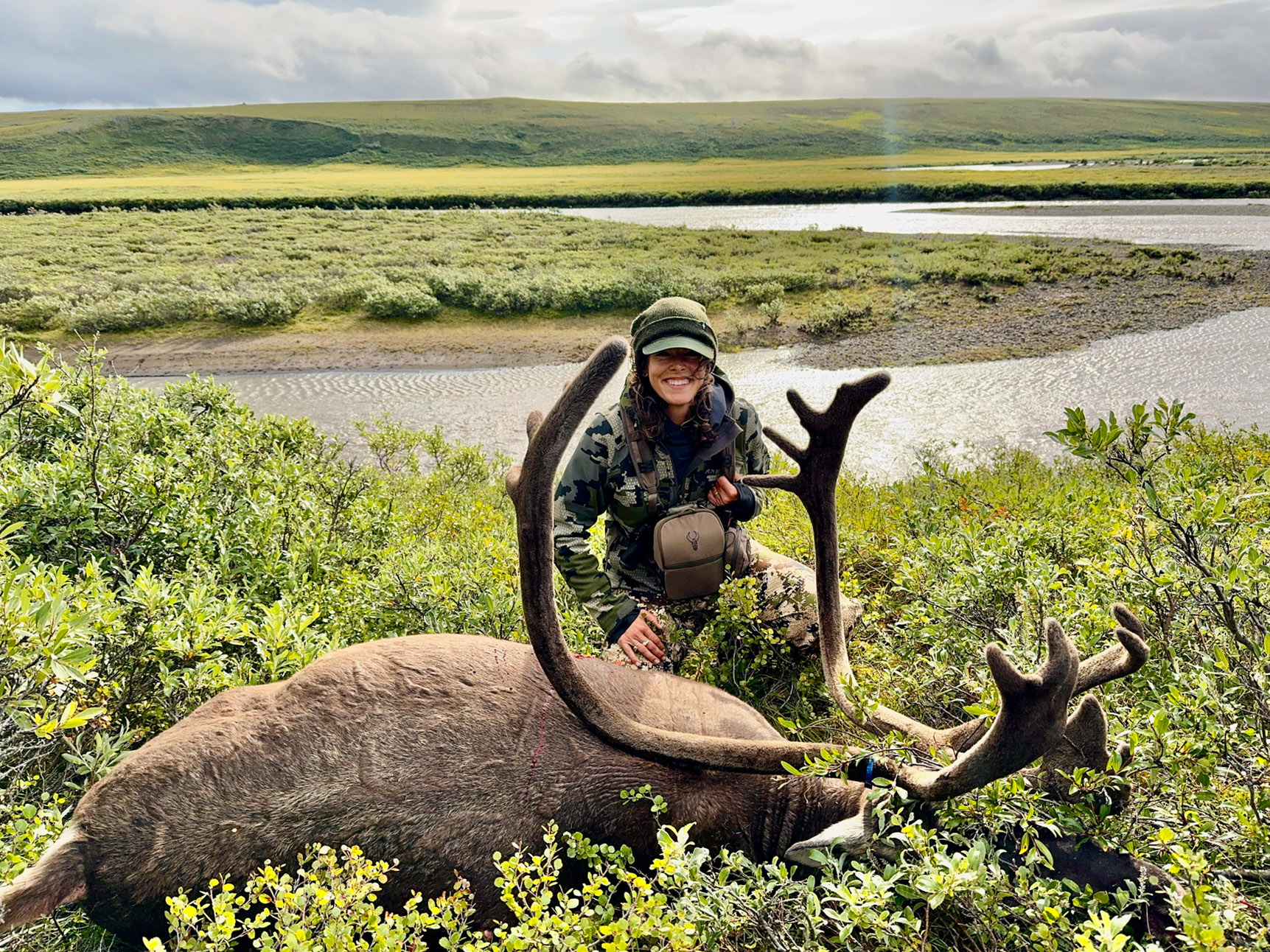 A hunter sits by a caribou