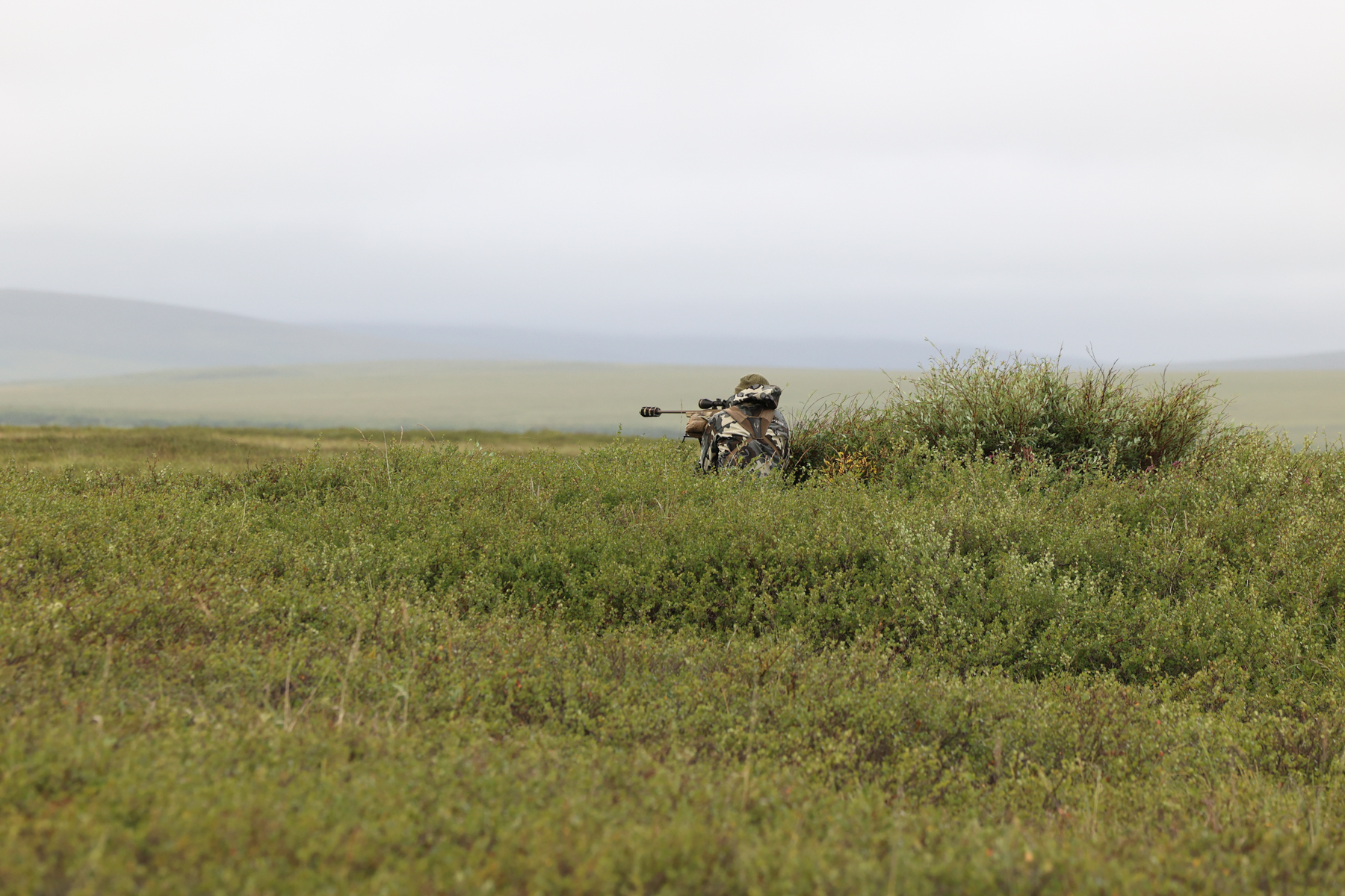A hunter settles on his rifle.
