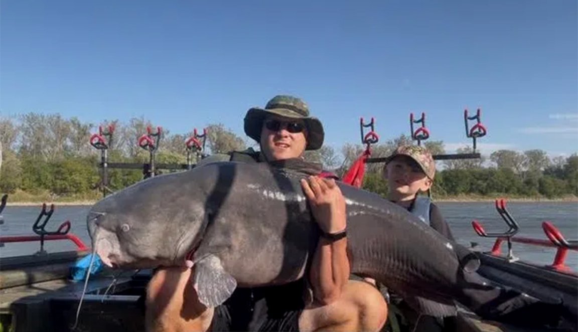 A Nebraska fisherman holds up a giant blue catfish.