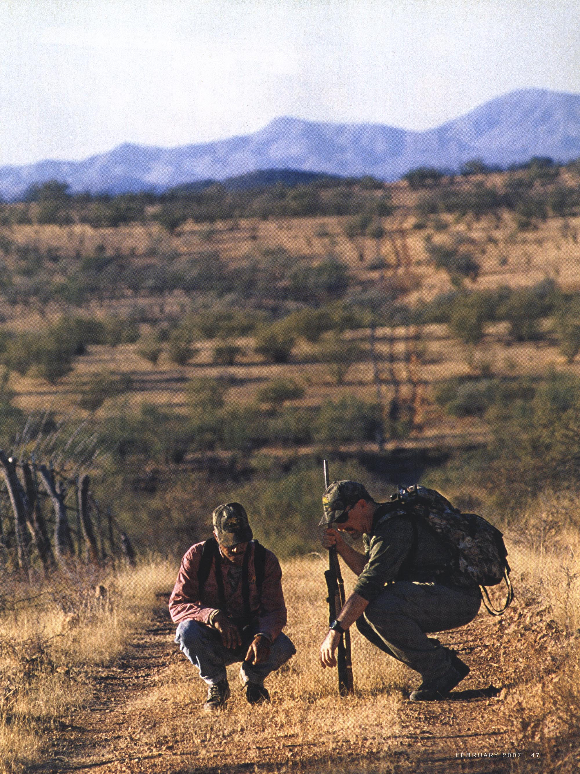 A photo of two hunters examining tracks in the road.