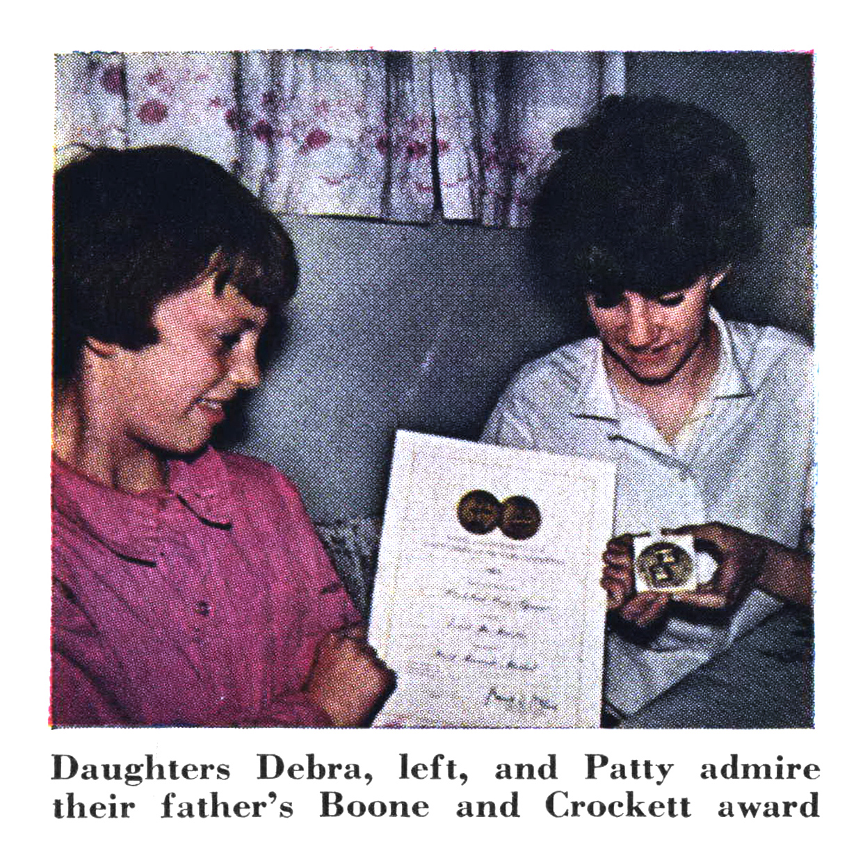 A photo of two girls in the 1960s holding a Boone and Crockett award.