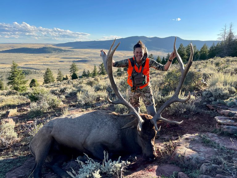 A hunter by an elk with sitka camo on