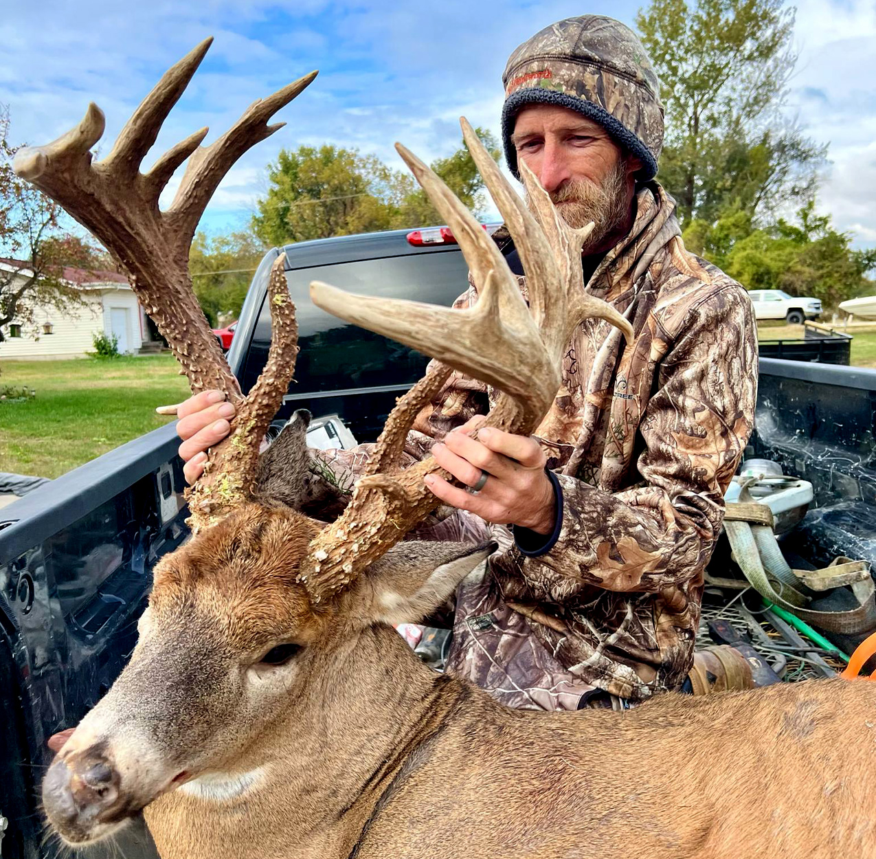 A Kansas hunter with a big buck in a truck bed.
