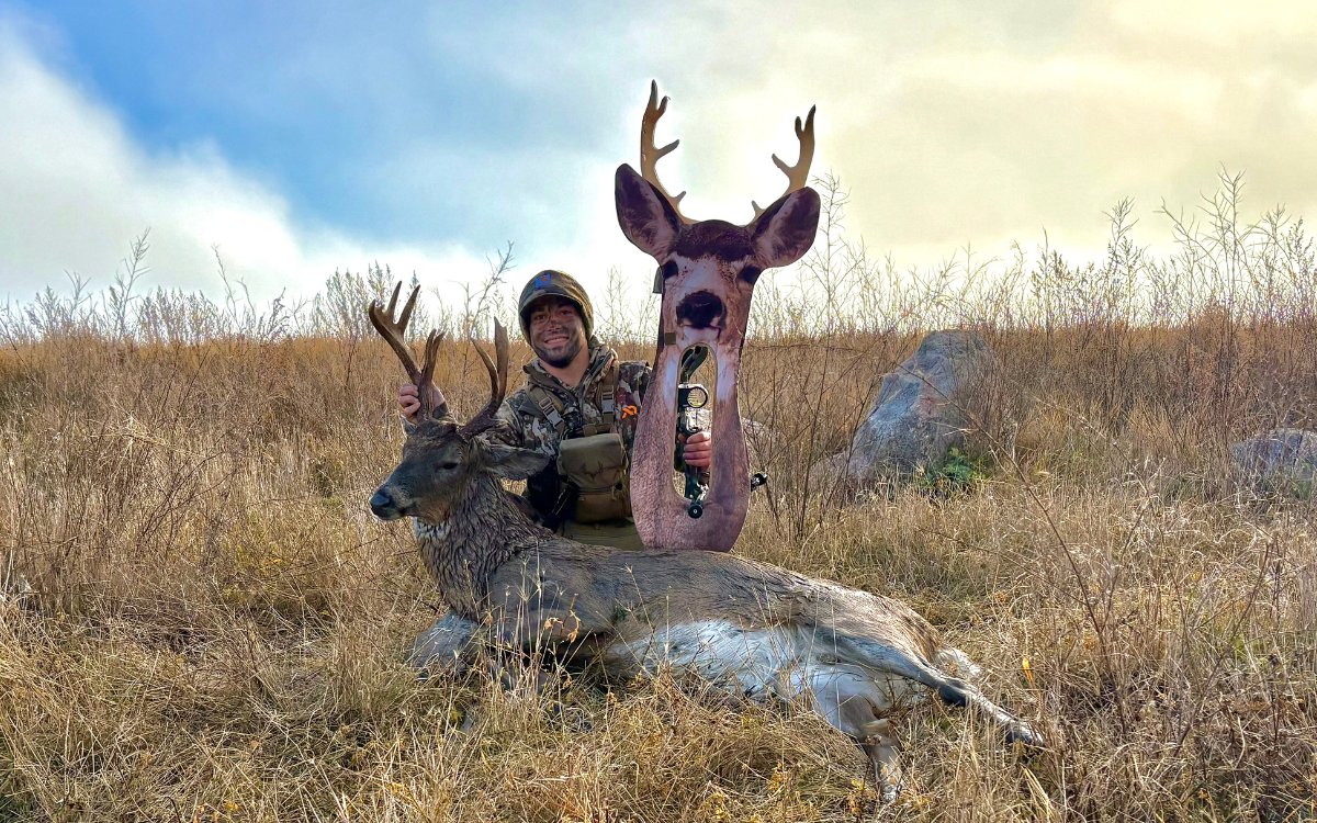 The author with a whitetail buck in the prairie while holding up his bow and decoy.
