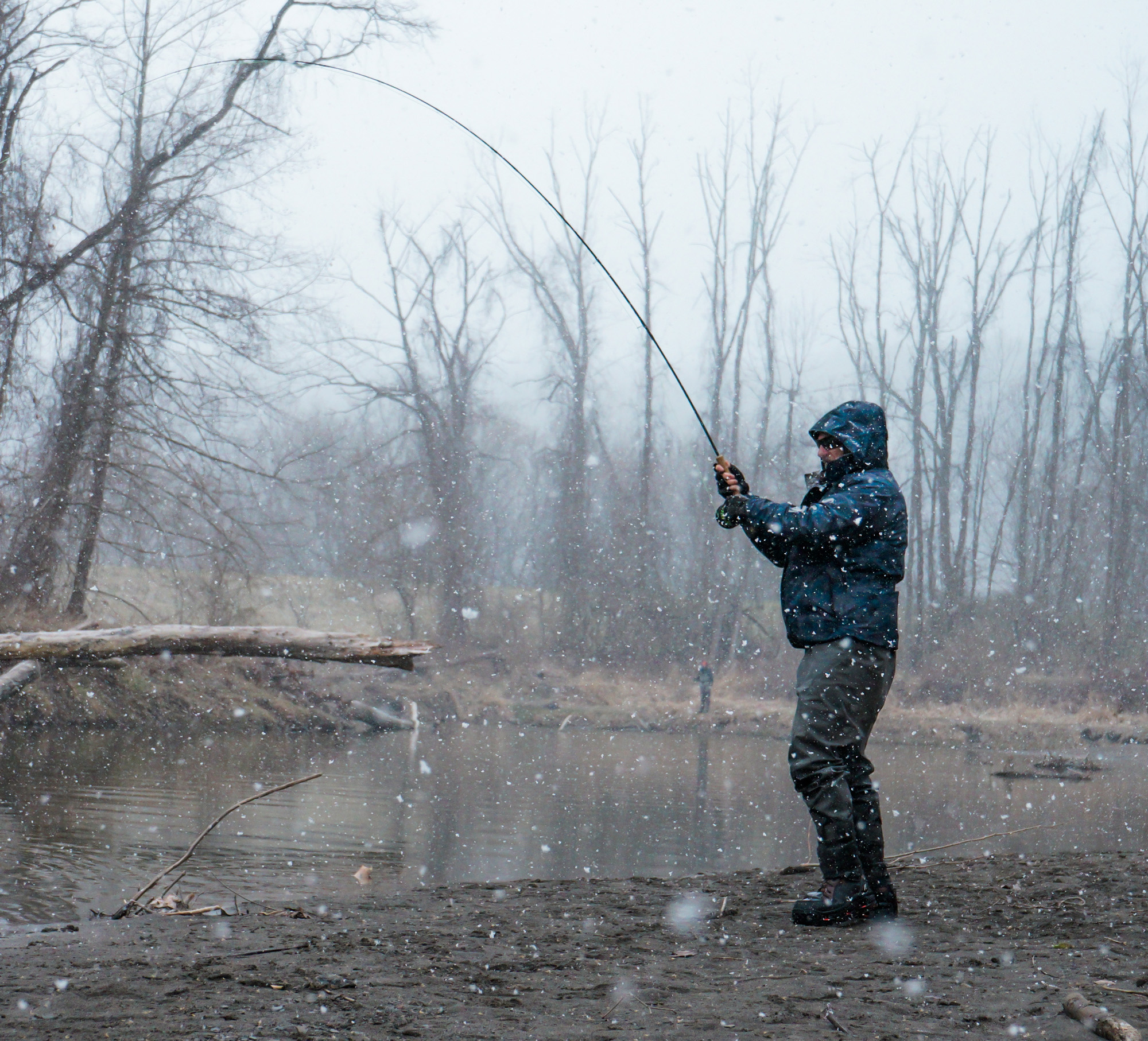 An angler hooks up in a cold wintery river.