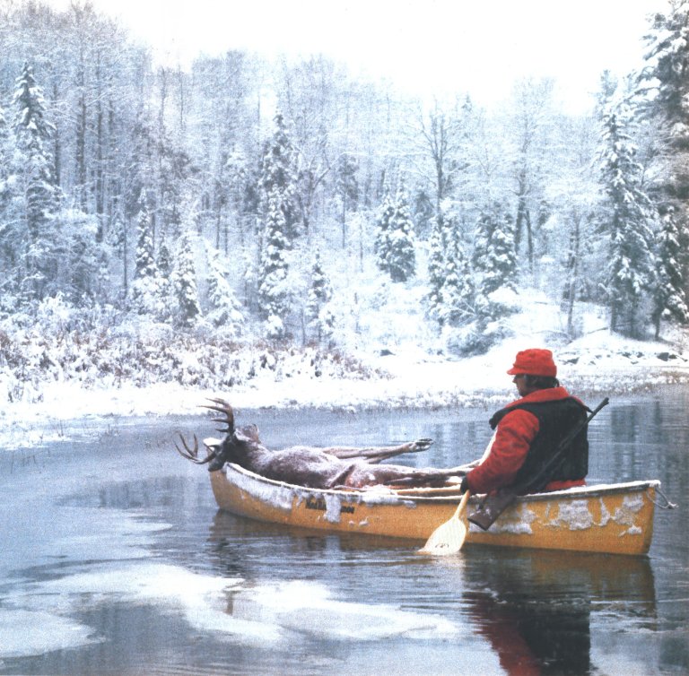 an old photograph of a hunter in a yellow canoe with a nice buck